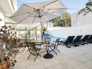 a table and chairs with an umbrella on a patio at Maresia Villa Mar in Nazaré