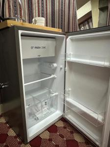 an empty refrigerator with its door open in a room at Holly Hills Guesthouse Ras Al Jinz in Junayz al Janūbī