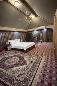 a bedroom with a bed and a rug at Holly Hills Guesthouse Ras Al Jinz in Junayz al Janūbī