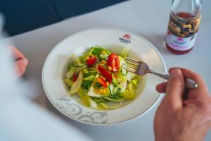 a person eating a bowl of salad with a fork at Frich's Rudshøgda in Ringsaker