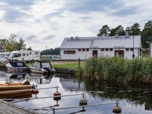a white building with boats in the water next to a river at Nävekvarns Skärgårdscamping in Nävekvarn