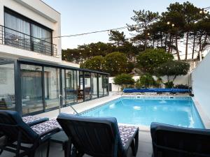 a swimming pool with chairs and a building at Maresia Villa Mar in Nazaré