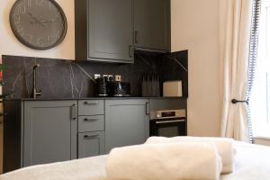 a kitchen with gray cabinets and a clock on the wall at Lovely Studio Flat on Bath Road - Flat 10 in Bristol