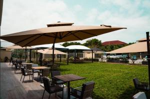 a row of tables and chairs under a large umbrella at Alisa Hotel North Ridge in Accra