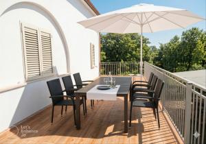 a table and chairs on a balcony with an umbrella at Villa Antonina & Mino in Cala Liberotto