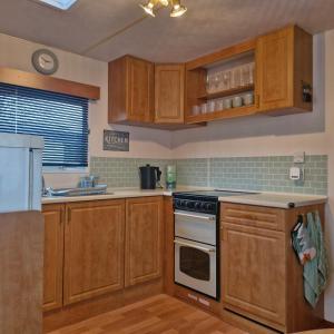 a kitchen with wooden cabinets and a stove top oven at Palm Court - 3 Bed Heated Pool Parking Nr Beach in Par
