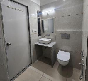 a bathroom with a white toilet and a sink at Omisha Stay & Pavilion in Sehore