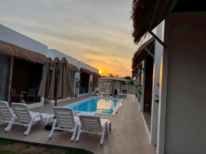 a patio with chairs and a pool with a sunset at The Pool House Koh Lanta in Ko Lanta