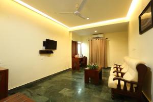 a living room with a couch and a tv at Hotel Indraprastha varkala in Varkala