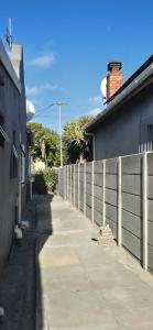 a sidewalk next to a fence next to a house at Relax Guest House in Goodwood