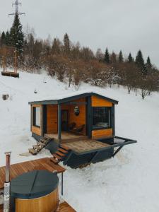 a tiny house in the snow with a deck at Putyscha house in Tukhlya