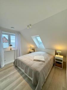 a bedroom with a bed with two lamps and two windows at Vollmöblierte hochwertige neue Apartments in Klevendeich