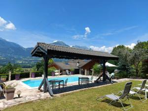 a pool with a pergola next to a house at Chalet romantique avec piscine in Monthion