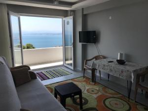 a living room with a couch and a table and a large window at Kuğu Apart Pansiyon in Sinop