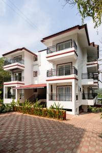 a white building with balconies and a brick driveway at Staymaster Encanto - Serviced 2BHK in Siolim