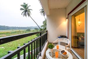 a balcony with a table and a view of a palm tree at Staymaster Encanto - Serviced 2BHK in Siolim