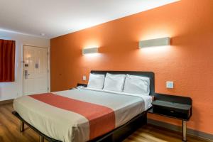 Habitación de hotel con cama con pared de color naranja en Motel 6-San Antonio, TX - South WW White Rd, en San Antonio