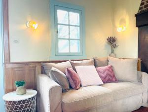 a couch with pillows on it in a living room at La Longère au Fil des Saisons in Favières