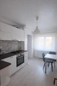 a kitchen with white cabinets and a table and a dining room at Sara Apartment Centru Râmnicu Vâlcea in Râmnicu Vâlcea