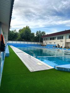 a large swimming pool with green grass next to a building at Avenue Hotel Tashkent in Tashkent