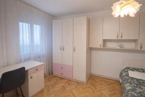 a bedroom with white cabinets and a desk and a bed at Sara Apartment Centru Râmnicu Vâlcea in Râmnicu Vâlcea