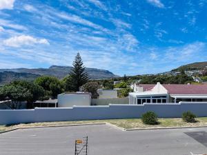 a white fence in front of a house with mountains at Capri Horizon Hideaway in Fish Hoek