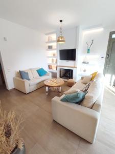 a living room with two white couches and a fireplace at Harmony garden house in Porto Rafti