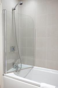a shower with a glass door next to a bath tub at The bucks head in Church Stretton