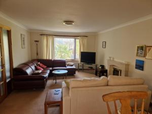 a living room with a couch and a tv at Brandane in Brodick +2 photos