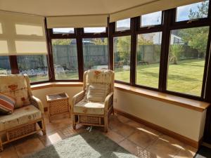 a living room with two chairs and windows at Brandane in Brodick