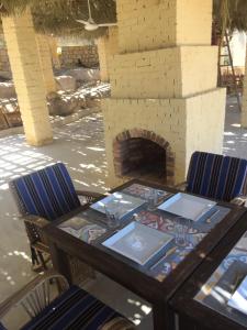 a table and chairs with a table and a fireplace at Kom El Dikka Agri Lodge in ‘Izbat an Nāmūs