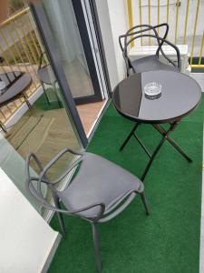 a table and chairs on a balcony with green carpet at APARTAMENT DOMINA - deluxe - self check-in, aer conditionat, oază de liniște, sentimentul de acasă in Sînnicolau Mare
