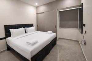 a bedroom with a large bed with white sheets at Orin Suites Gachibowli in Hyderabad
