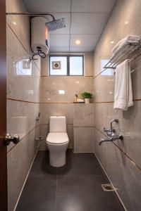 a bathroom with a toilet and a shower and a sink at Orin Suites Gachibowli in Hyderabad