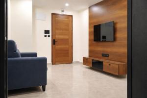 a living room with a tv and a blue couch at Orin Suites Gachibowli in Hyderabad