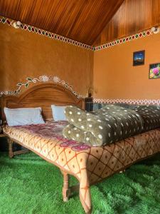 a bedroom with a large bed with a wooden headboard at Mhara Himachal in Bīr