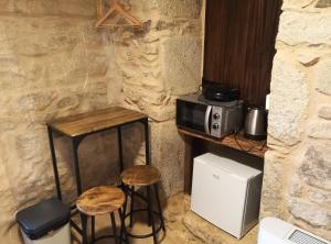 a kitchen with a microwave and two stools at Pensión A Lubre in Fisterra