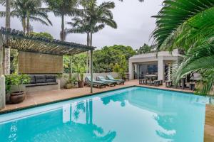 a swimming pool in a house with palm trees at Beach Forest Lodge - Milkwood in Ballito
