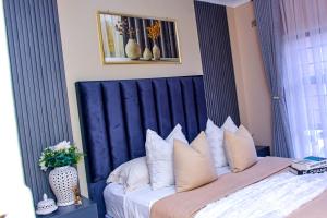 a bed with a blue headboard and a vase of flowers at Kunashe Apartments in Harare +4 photos