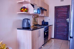 a kitchen with wooden cabinets and a stove top oven at Kunashe Apartments in Harare