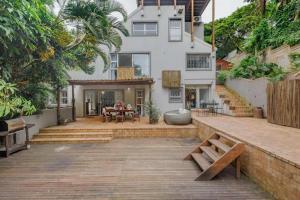 a house with a large patio with a wooden deck at Beach Forest Lodge - Milkwood in Ballito