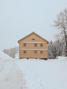 a building in a snow covered field with trees at Hirschberg 231 in Bizau