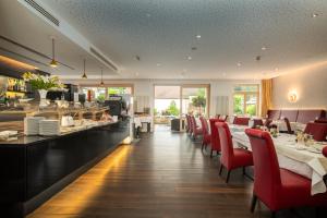 a restaurant with a long table and red chairs at Aqua Aurelia Suitenhotel an den Thermen in Baden-Baden