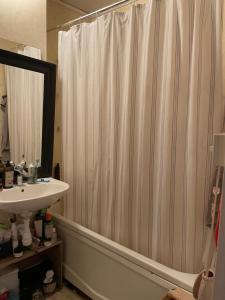 a bathroom with a shower curtain and a sink at Big Room in shared apartment in Kungälv