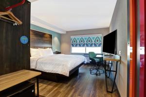 a hotel room with a bed and a desk with a computer at Tru By Hilton Edmonton Windermere in Edmonton +27 photos