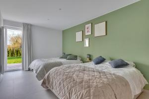 two beds in a bedroom with green walls at 't Vennehuys - vakantiehuis nabij Bokrijk in Genk