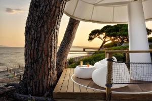 a table with an umbrella next to a tree at The Sense Experience Resort - Preferred Hotels & Resorts in Follonica