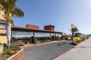 an empty street in front of a building with palm trees at BLUESEA Aloe Corralejo in Corralejo