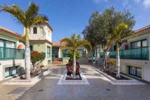 a courtyard with palm trees in front of a building at BLUESEA Aloe Corralejo in Corralejo