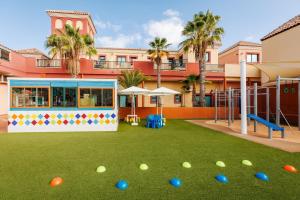 a playground with balls on the grass in front of a building at BLUESEA Aloe Corralejo in Corralejo +66 photos